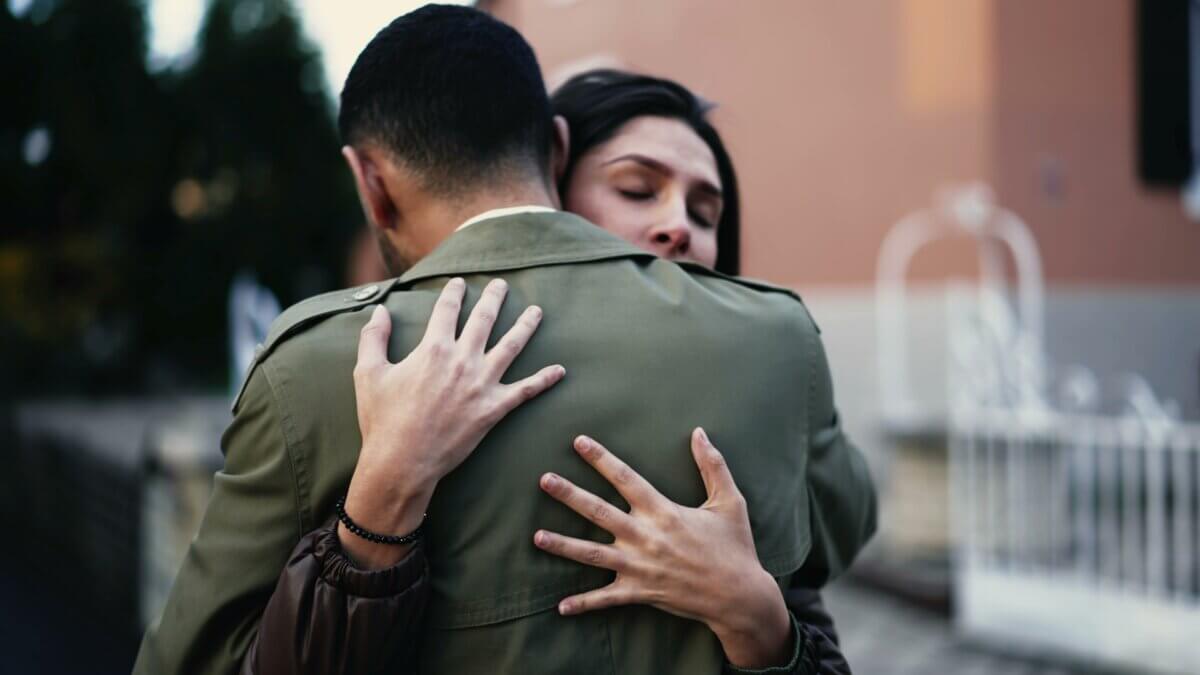 A couple hugs outside as if to say goodbye or mourn