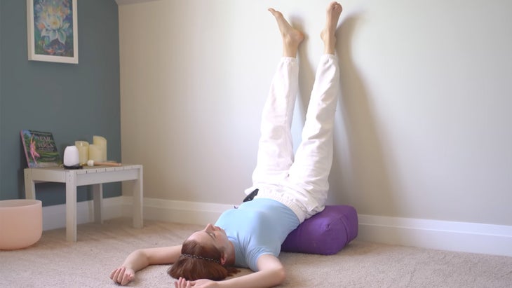 woman practicing yoga with legs against a wall in a traditional pose with legs together