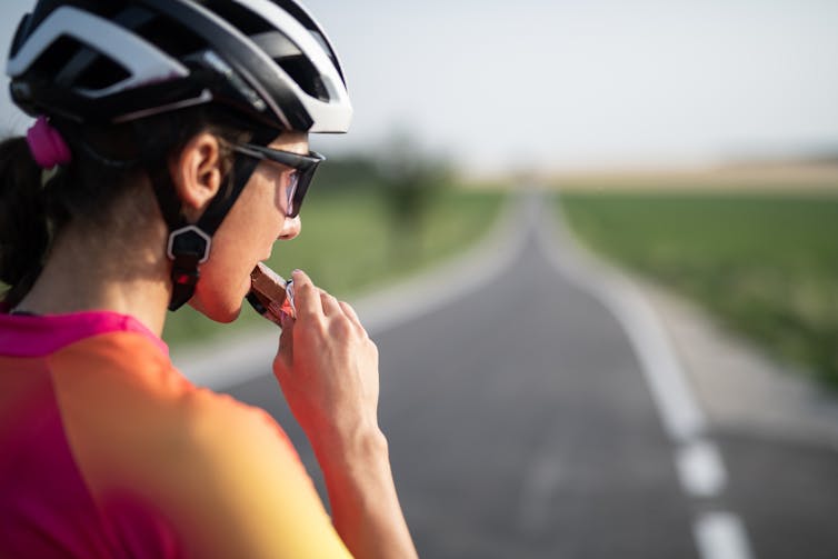 A cyclist eats a protein bar and looks at the road