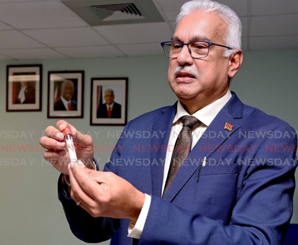 Health Minister Terrence Deyalsingh, left, holds a test tube containing mosquito larvae in clean water during a press conference at the San Fernando University Teaching Hospital on July 26. - Photo by Venessa Mohammed