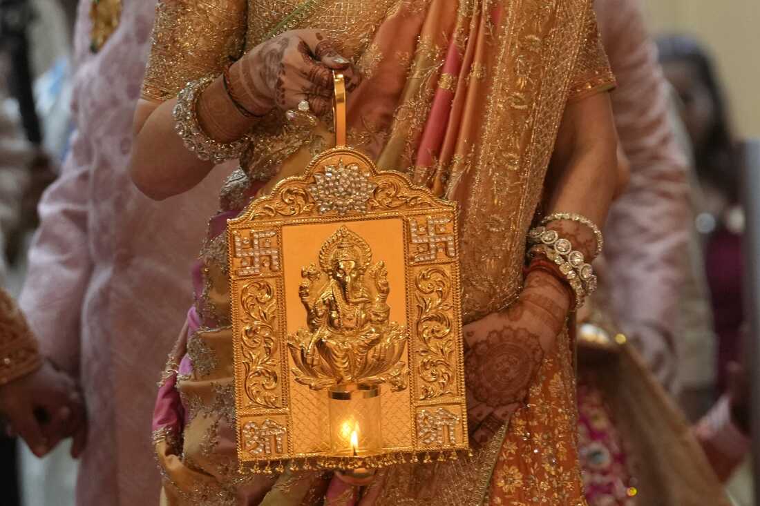 Nita Ambani, wife of Asia's richest man Mukesh Ambani, arrives holding a lamp with an image of the elephant-headed Hindu god Ganesh, for the wedding of their youngest son Anant Ambani in Mumbai on Friday.