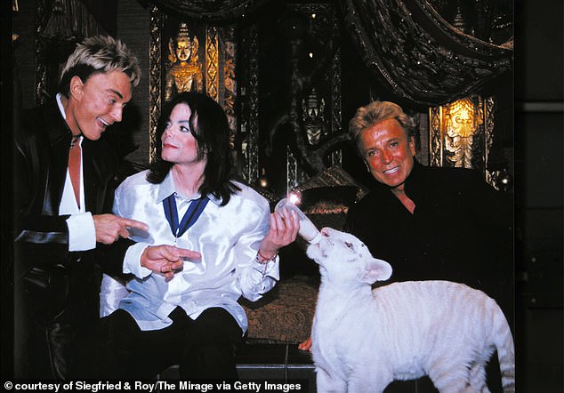 Siegfried and Roy pose for a portrait with Michael Jackson and a white tiger in their enclosure at the Mirage Hotel in March 1990