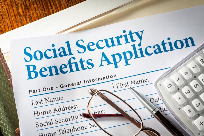 A pair of glasses, a pen and a calculator rest on a Social Security application form.