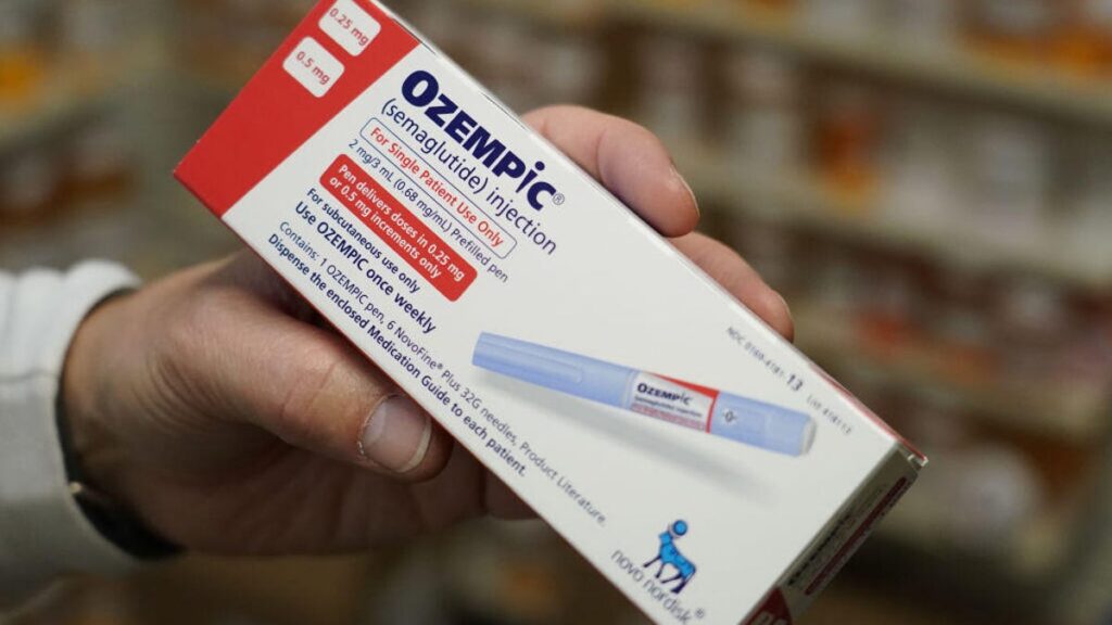 A pharmacist&apos;s hand holding a box of Ozempic