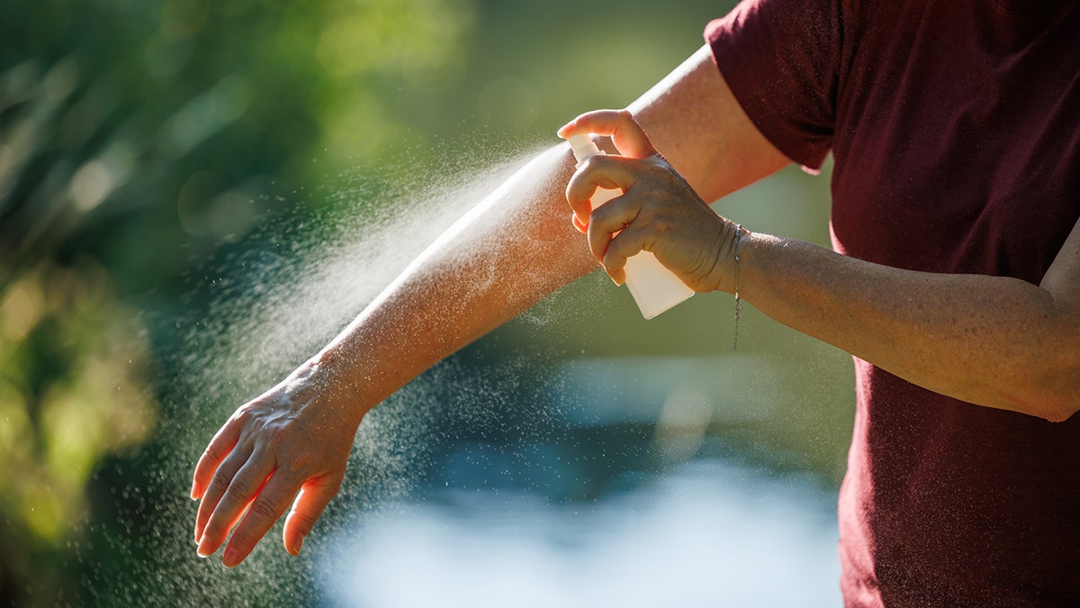 a person applies insect repellent to his arm