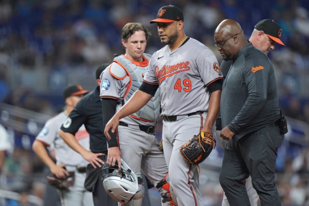 Orioles starting pitcher Albert Suarez steps out with trainer after...