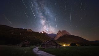 streaks of light cross the starry sky above a mountain range