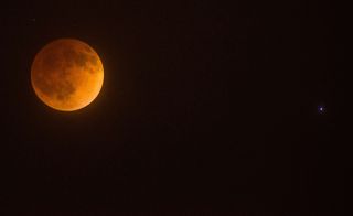 a bright blue star next to the moon in the dark night sky